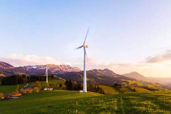 Windturbine in een groen heuvellandschap bij zonsopkomst